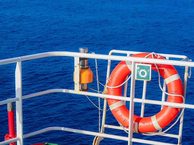 Lifebuoy on vessel deck with ocean background, symbolizing maritime safety and security.