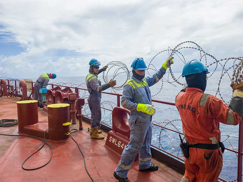 Synergy team enhancing maritime security on vessel deck by installing anti-piracy steel wires.