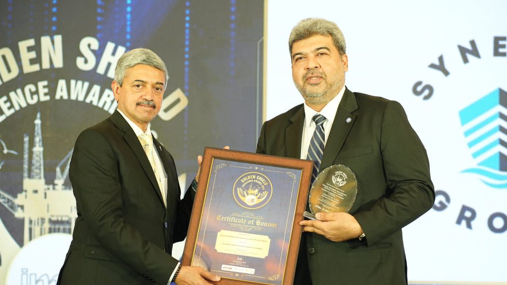 Maneesh Pradhan accepts an award and certificate at the IMC Awards 2026 ceremony, standing on stage during the presentation.