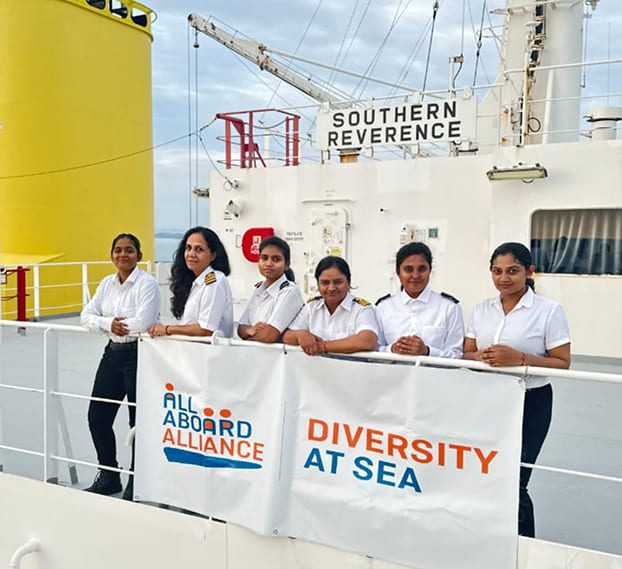 Female seafarers standing on the deck of vessel SOUTHERN REVERENCE with All Aboard Alliance, Diversity At Sea banner